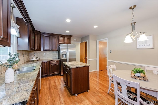 kitchen with dark brown cabinetry, stainless steel fridge with ice dispenser, a sink, light wood-style flooring, and backsplash