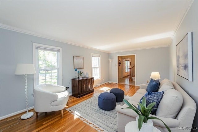 living area with baseboards, ornamental molding, and light wood finished floors