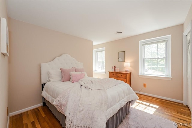 bedroom featuring multiple windows, light wood-style flooring, and visible vents