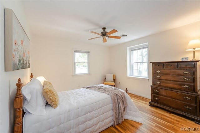bedroom featuring light wood-type flooring, a ceiling fan, baseboards, and visible vents