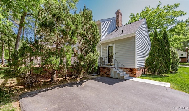 rear view of property with a chimney, a shingled roof, and a patio area