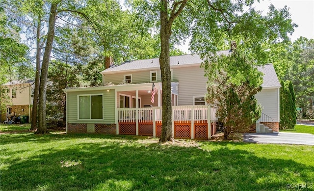 rear view of property featuring a shingled roof, a wooden deck, a yard, and a chimney