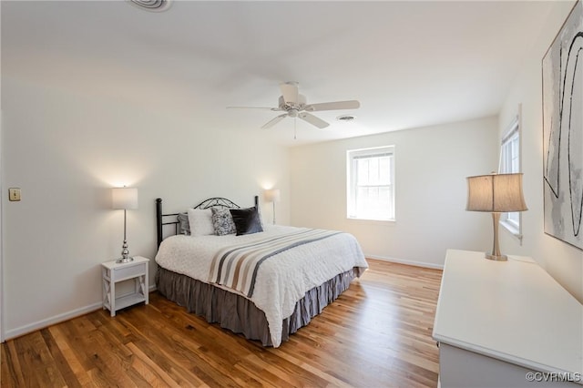 bedroom with baseboards, ceiling fan, wood finished floors, and visible vents