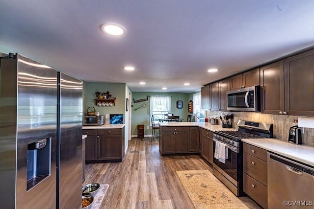 kitchen featuring recessed lighting, light countertops, a peninsula, light wood-style flooring, and appliances with stainless steel finishes