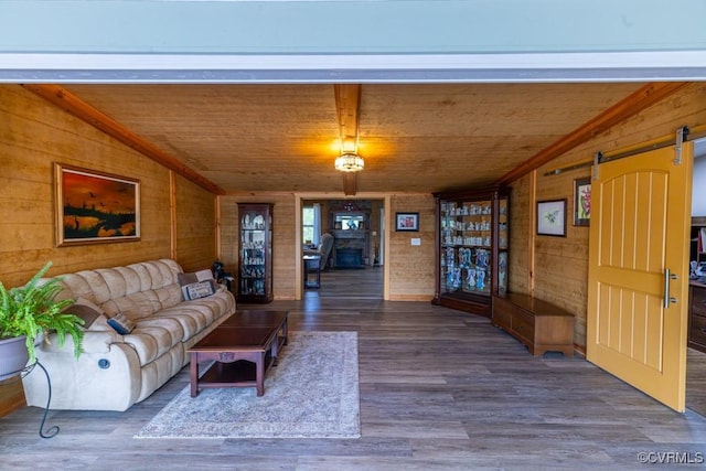 living room with a barn door, vaulted ceiling, wood finished floors, wooden ceiling, and wood walls