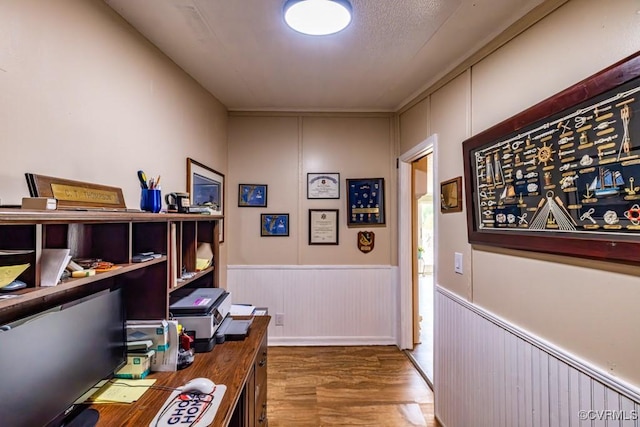 office featuring a wainscoted wall, wood finished floors, and a decorative wall
