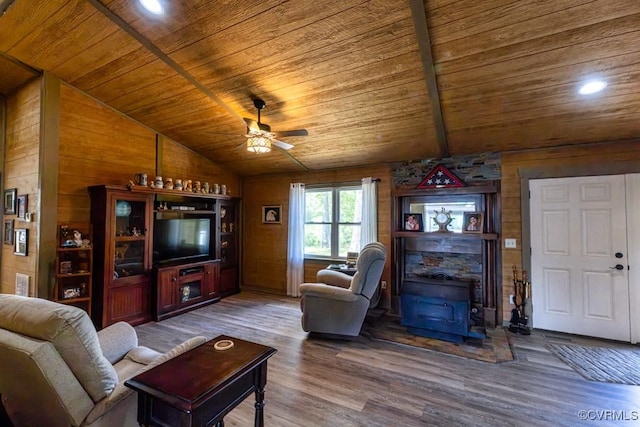 living room featuring wood ceiling, vaulted ceiling, a wood stove, and wood finished floors