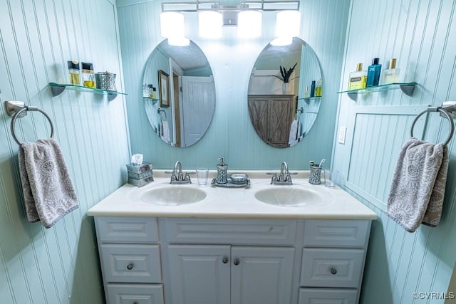 bathroom with wood walls, a sink, and double vanity