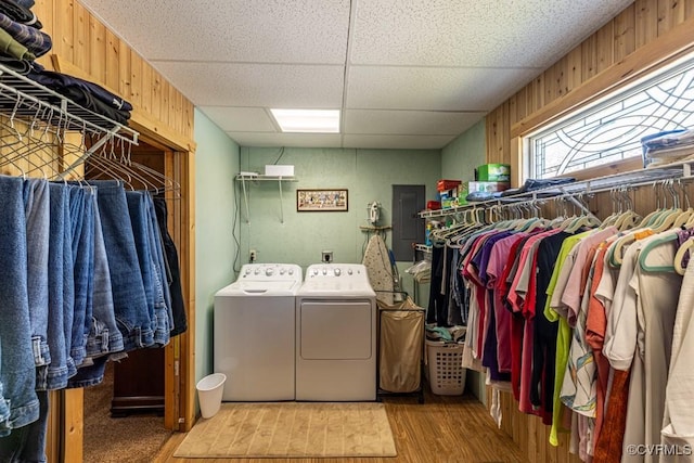 laundry room with wooden walls, wood finished floors, independent washer and dryer, and laundry area
