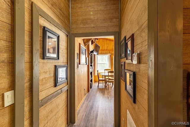 hall with wood walls, wood finished floors, and visible vents