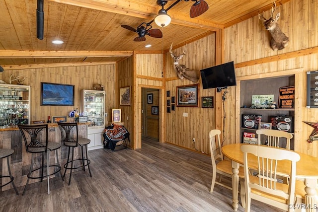 dining space with wood finished floors, wooden ceiling, wooden walls, and a ceiling fan