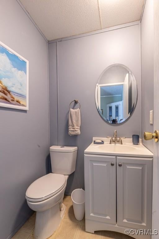 half bathroom featuring tile patterned flooring, toilet, and vanity