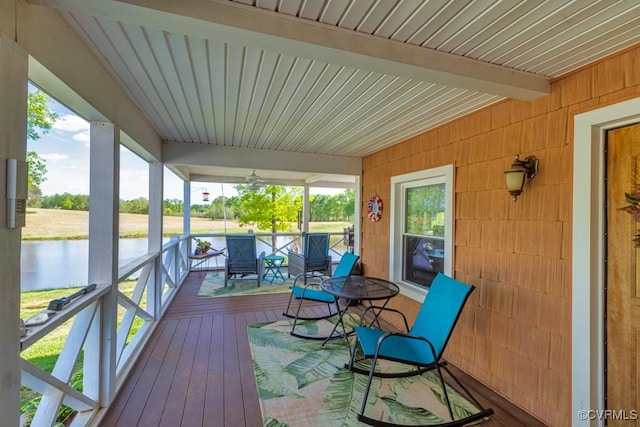 sunroom featuring beam ceiling, a water view, and a healthy amount of sunlight
