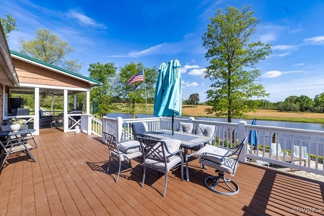 wooden deck with outdoor dining area and a water view