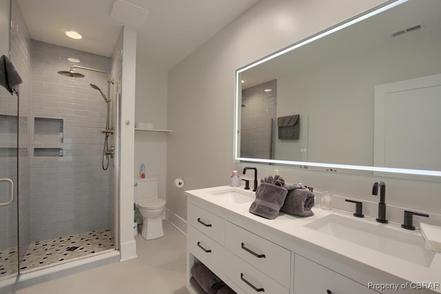 bathroom with double vanity, a shower stall, toilet, and a sink