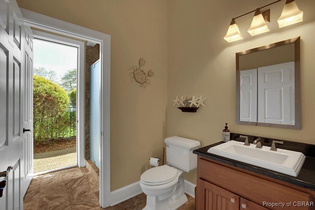 bathroom featuring toilet, vanity, and baseboards