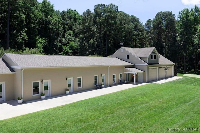 rear view of property featuring a yard, an attached garage, and stucco siding
