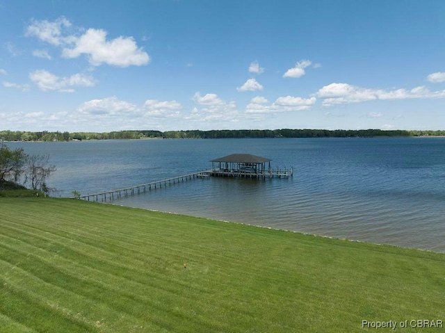 view of dock with boat lift, a water view, and a yard