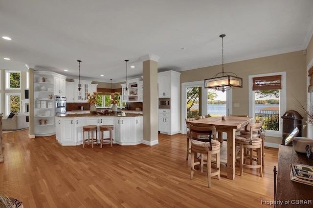 dining space featuring ornamental molding, light wood-style flooring, and plenty of natural light