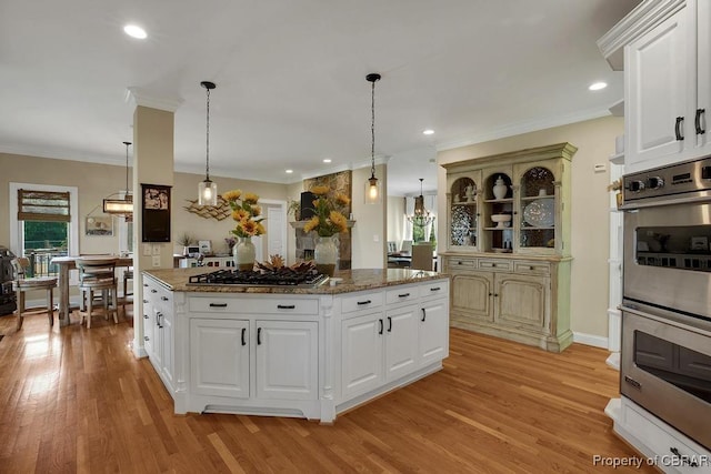 kitchen featuring light wood-type flooring, a center island, pendant lighting, and stainless steel appliances