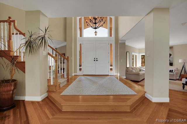entrance foyer with a wealth of natural light, a notable chandelier, stairs, and baseboards