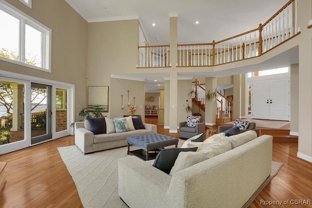 living room with wood finished floors, stairs, a towering ceiling, baseboards, and ornamental molding