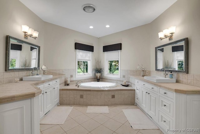 bathroom with tile patterned flooring, a bath, a sink, and two vanities