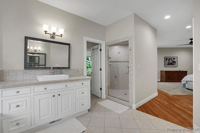 ensuite bathroom with a shower stall, tile patterned floors, vanity, baseboards, and visible vents