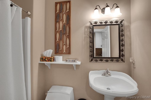 full bath featuring a sink, a shower with shower curtain, and toilet
