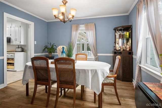 dining space with a chandelier, light wood-type flooring, crown molding, and baseboards
