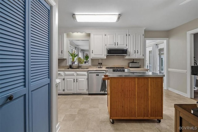 kitchen featuring stainless steel appliances, a sink, white cabinetry, and stainless steel counters