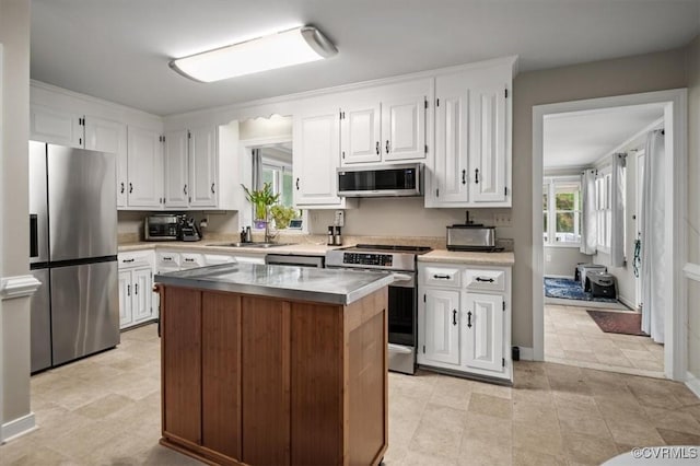 kitchen with stainless steel appliances, a sink, white cabinets, and a kitchen island