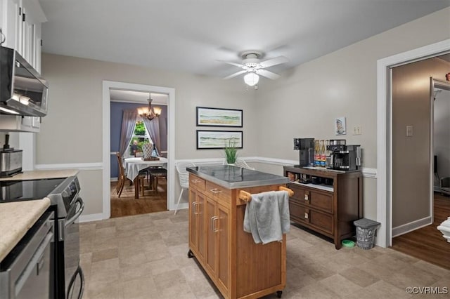 kitchen with stainless steel appliances, a chandelier, brown cabinets, a ceiling fan, and baseboards
