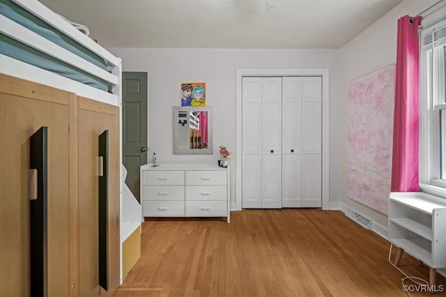 bedroom featuring light wood finished floors, baseboards, and a closet