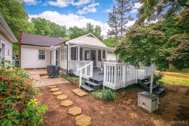 back of property featuring a sunroom, a deck, and a chimney