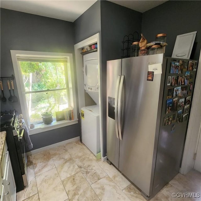 kitchen featuring stacked washer and dryer, light countertops, baseboards, and stainless steel appliances