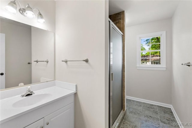full bath featuring vanity, a stall shower, and baseboards