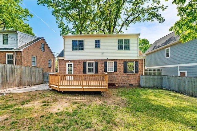 back of house featuring a yard, brick siding, a wooden deck, and a fenced backyard