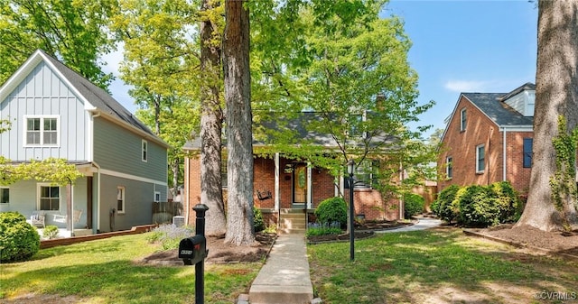 view of front of home with brick siding, board and batten siding, a porch, and a front yard
