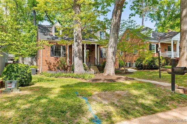 view of front facade with cooling unit, a front yard, fence, and brick siding
