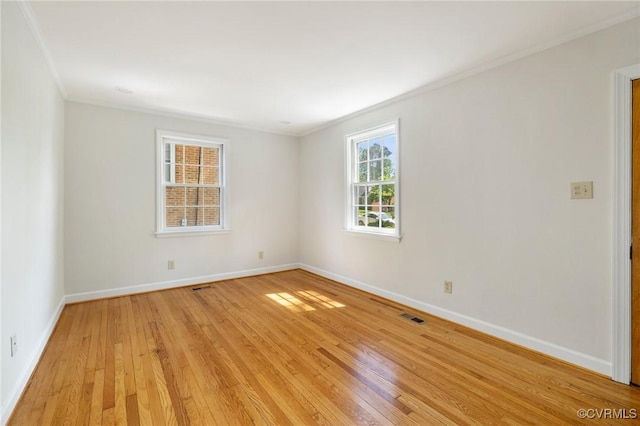 empty room featuring ornamental molding, visible vents, light wood-style flooring, and baseboards