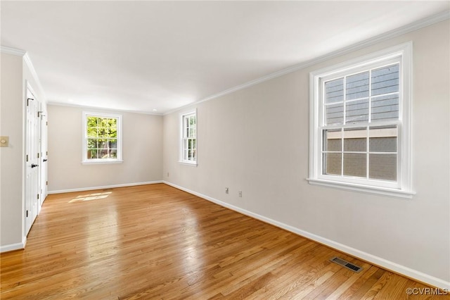 empty room with visible vents, crown molding, and baseboards