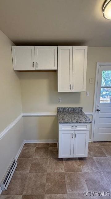 501 Faye St, Richmond, VA 23225 - kitchen featuring white cabinets, dark stone countertops, stone finish flooring, baseboards, and a baseboard radiator