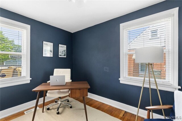 office area featuring baseboards, wood finished floors, and visible vents