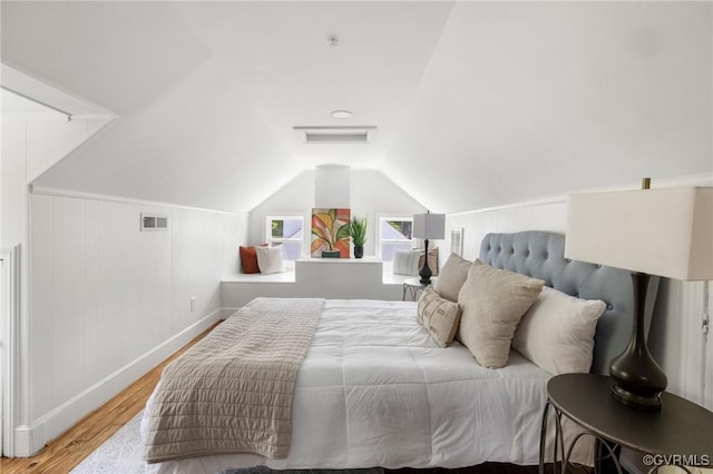 bedroom with baseboards, visible vents, wood finished floors, and vaulted ceiling
