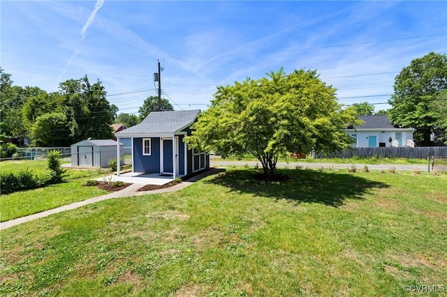 view of front of property featuring a storage shed, a front lawn, fence, and an outbuilding