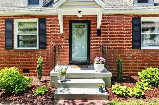 doorway to property with brick siding and roof with shingles