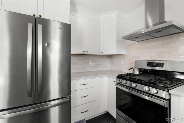 kitchen with decorative backsplash, appliances with stainless steel finishes, white cabinetry, light countertops, and wall chimney exhaust hood