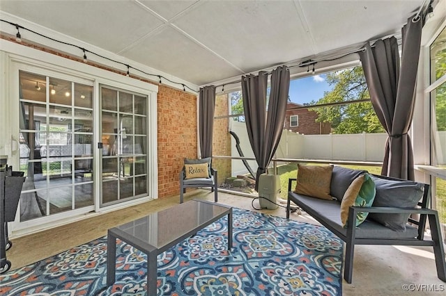 sunroom featuring brick wall