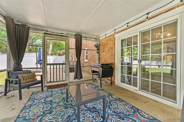 sunroom featuring brick wall and concrete flooring